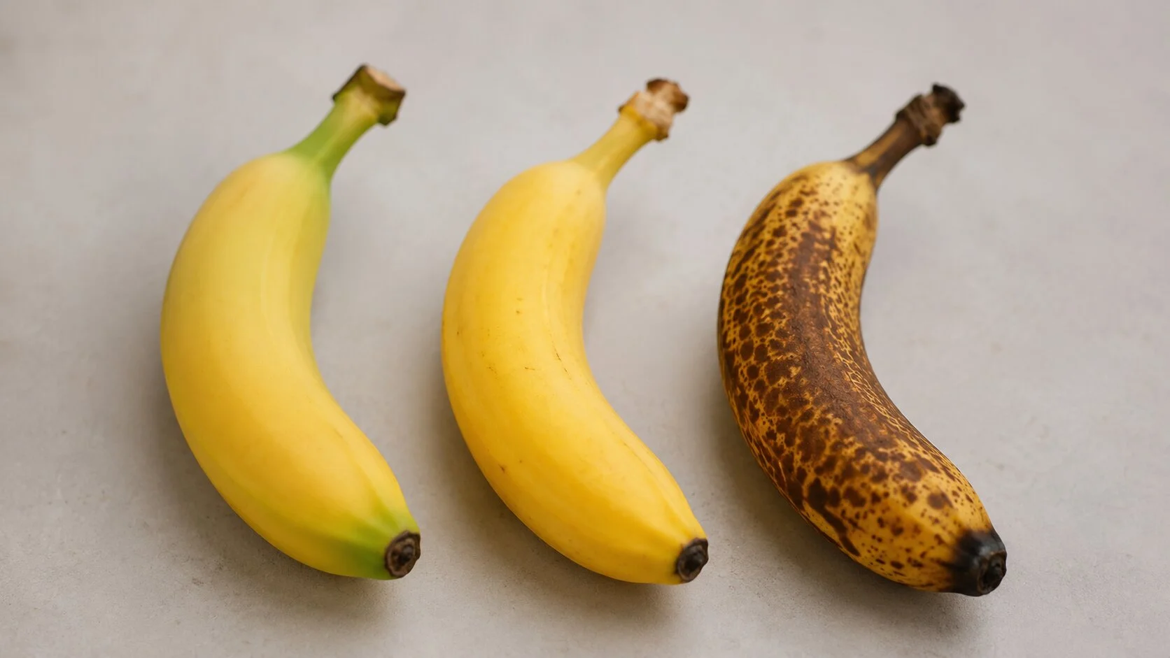 Trois bananes &agrave; trois stades de maturit&eacute;, de la banane ferme &agrave; pointe verte &agrave; la banane tachet&eacute;e de brun